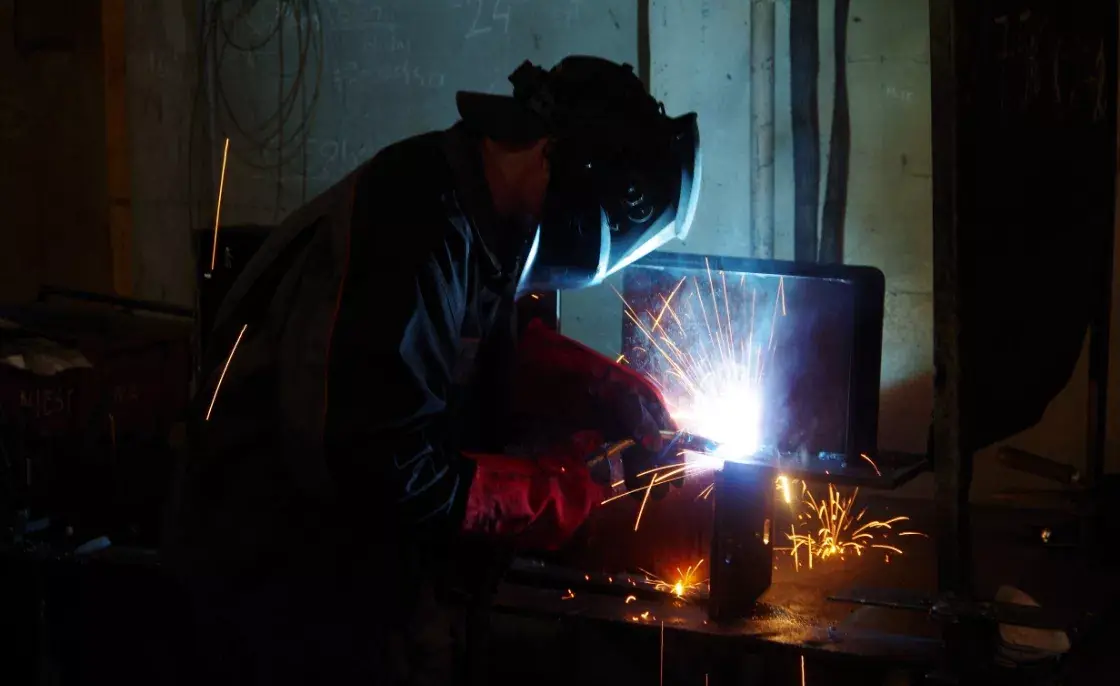 spawacz pracujący w mroku swojego warsztatu